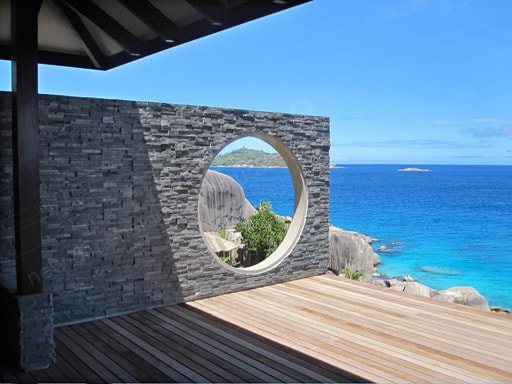 Norstone Charcoal Rock Panels on a Feature Wall in the Seychelles with a circular cut out showing granite formations and another Island in the distance